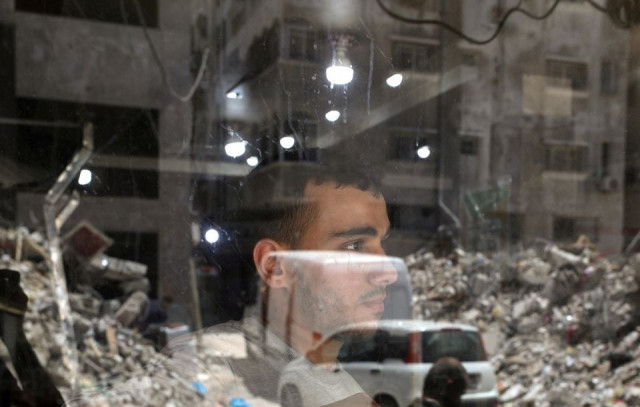 a palestinian man looks out as the remains of a building which was destroyed in israeli air strikes are reflected in a window amid israeli palestinian fighting in gaza may 20 2021 photo reuters a palestinian man looks out as the remains of a building which was destroyed in israeli air strikes are reflected in a window amid israeli palestinian fighting in gaza may 20 2021 photo reuters