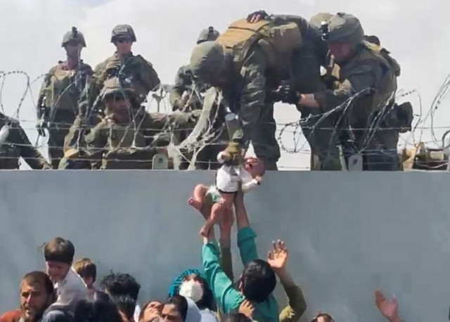 a baby is handed over to the american army over the perimeter wall of the airport for it to be evacuated in kabul afghanistan august 19 2021 photo reuters