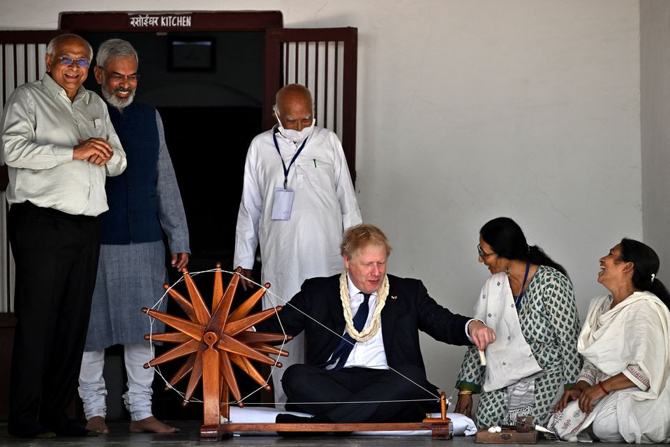 british prime minister boris johnson spins khadi on a charkha or a spinning wheel during his visit to the sabarmati ashram also known as gandhi ashram as india s environmental educator kartikeya sarabhai and the chief minister of gujarat state bhupendra patel look on in ahmedabad india april 21 2022 reuters