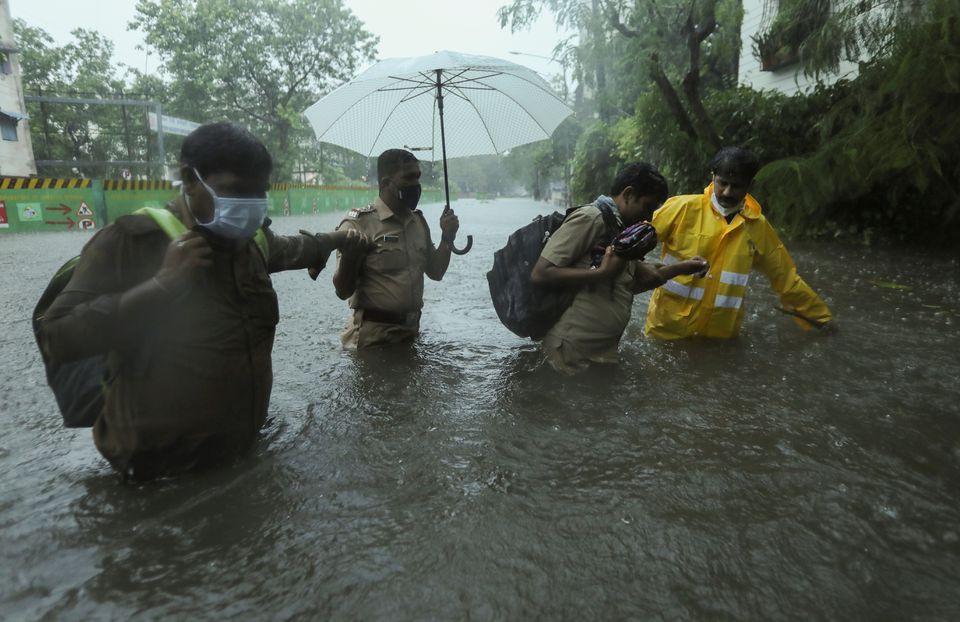 frontline workers help people cross a flooded street after heavy rainfall caused by cyclone tauktae in mumbai india photo reuters