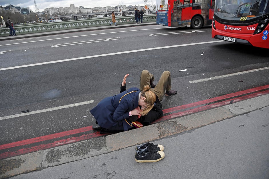 A woman assists an injured person after an incident on Westminster Bridge in London. PHOTO: REUTERS