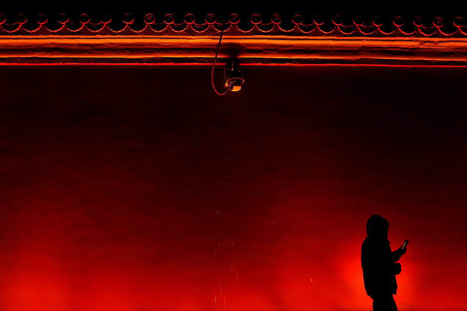 A man walks away under a security camera after taking pictures of the super blue moon from just outside the Forbidden City in Beijing, China. PHOTO: REUTERS