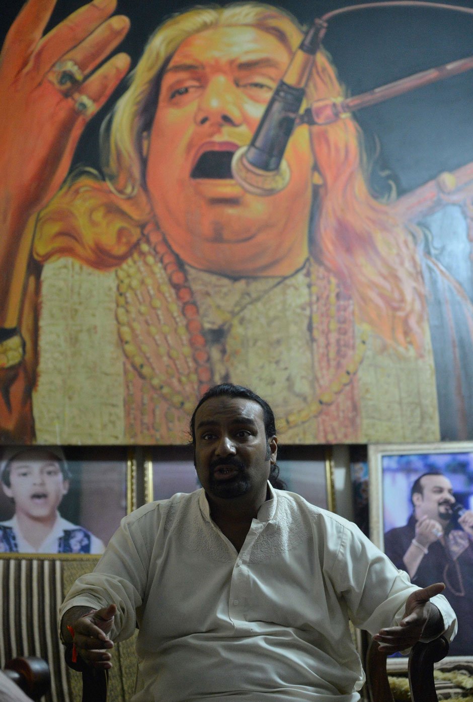 Qawwal Talha Sabri speaks during an interview with AFP behind an image of his late father and renowned Qawwal Ghulam Farid Sabri at his residence in Karachi. PHOTO: AFP