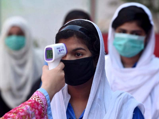 a school staffer checks the temperature of a student schools were reopened by the government on tuesday after the number of covid 19 cases declined in the province photo afp a school staffer checks the temperature of a student schools were reopened by the government on tuesday after the number of covid 19 cases declined in the province photo afp