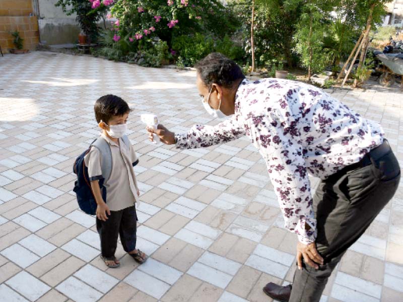 a staff member checks the temperature of a young student at a primary school in karachi on the first day that physical clas ses resumed for grade 8 and below across the province photo file