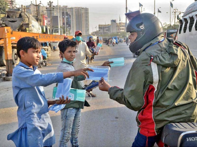 a motorcyclist stops to purchase face masks from young roadside vendors neither of whom are wearing masks as covid 19 cases continue to rise in karachi photo app a motorcyclist stops to purchase face masks from young roadside vendors neither of whom are wearing masks as covid 19 cases continue to rise in karachi photo app
