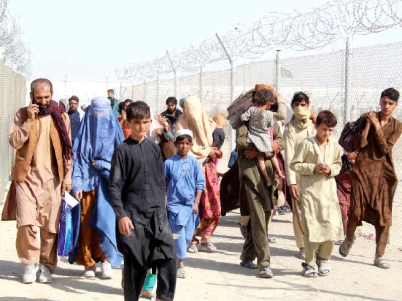 afghan nationals walk through a fenced corridor at the pak afghan border crossing point in chaman following the taliban s military takeover of afghanistan photo afp