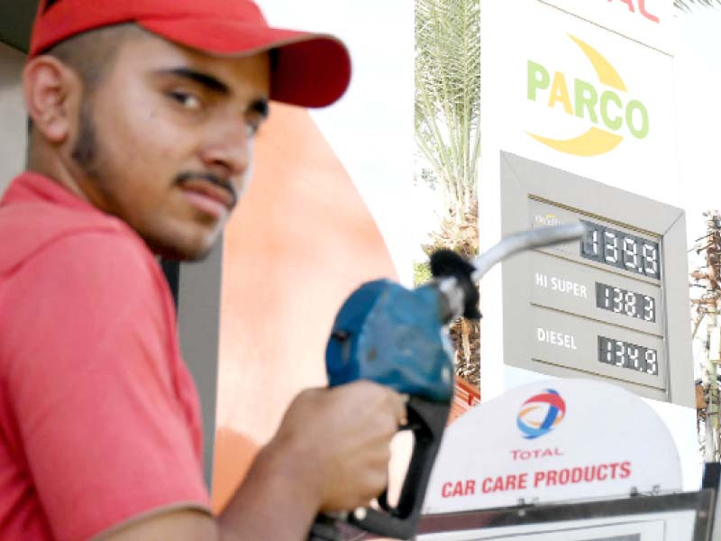 a worker refuels a vehicle at a patrol station while new fuel prices are shown on the screen photo online