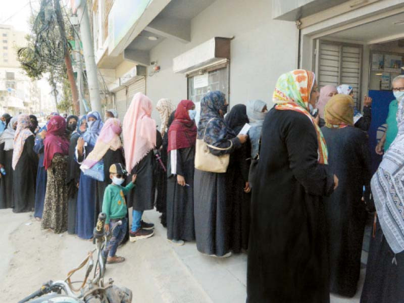 women health workers wait in line to draw their salaries from a bank branch this year s women march in karachi is dedicated to better wages security and equality photo jalal qureshi express