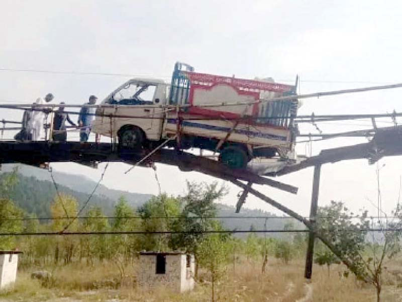 a vehicle is seen suspended in mid air on a collapsed wooden bridge installed over the kunhar river at shohal area near balakot photo express