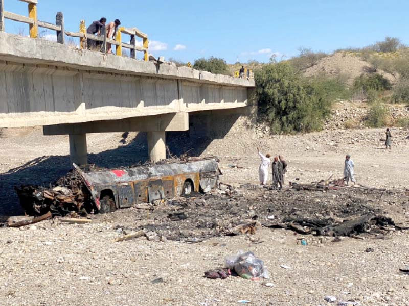 residents look at the wreckage of a burnt passenger bus at bela in lasbela district of balochistan photo afp