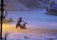 a motorcyclist wades through rainwater on a flooded road in the garrison city photos agha mehroz agencies