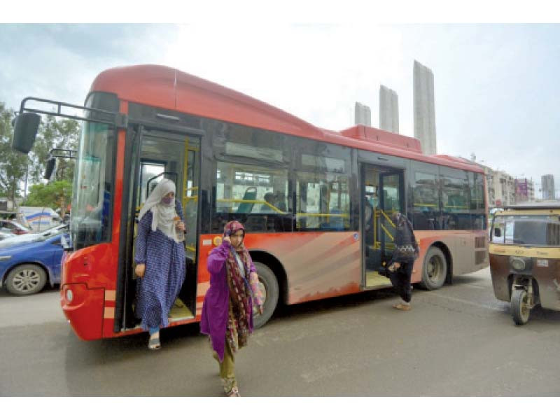 women get off a red bus on a road in the port city the public transport authority has yet to implement its ambitious plan of women bus drivers photo jalal qureshi express