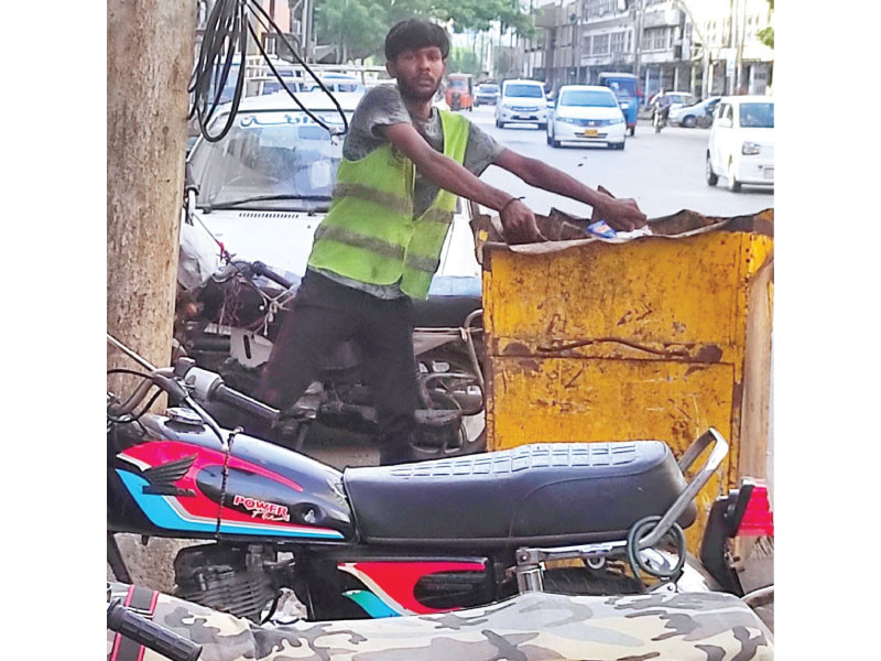 a sanitary worker picks up garbage without wearing gloves and face mask avoiding simple safety measures have caused skin and breathing disorders among sanitary workers photo razzak abro express
