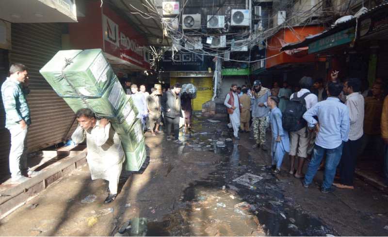 people shift their leftover goods to safe places after the fire destroyed their shops in a mobile market in saddar area on tuesday photo jalal qureshi express