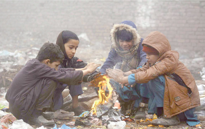 children sit around a fire to keep warm during foggy weather in peshawar photo app