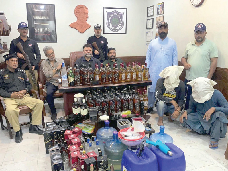 suspects with seized liquor sit with their faces covered at the excise police station on sunday photo ppi