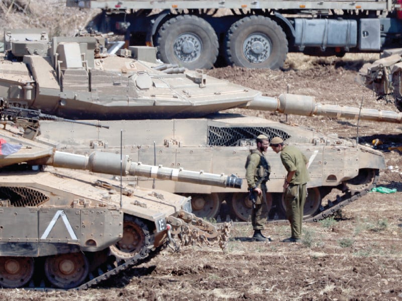 israeli members of the military stand next to armoured vehicles in northern israel photo reuters