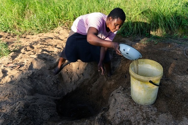 Celia Munhangu scoops through sand in search of water on the dried-up bed of the Mavhaire river in Buhera. PHOTO: AFP