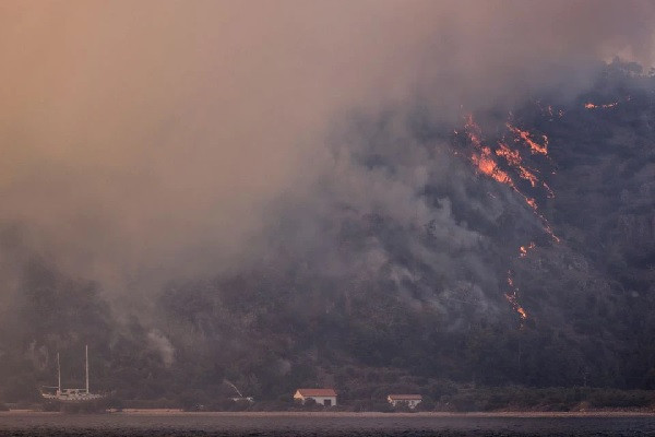 flames threat houses and a boat during a wildfire on the shores of cokertme village near bodrum turkey august 2 2021 photo reuters