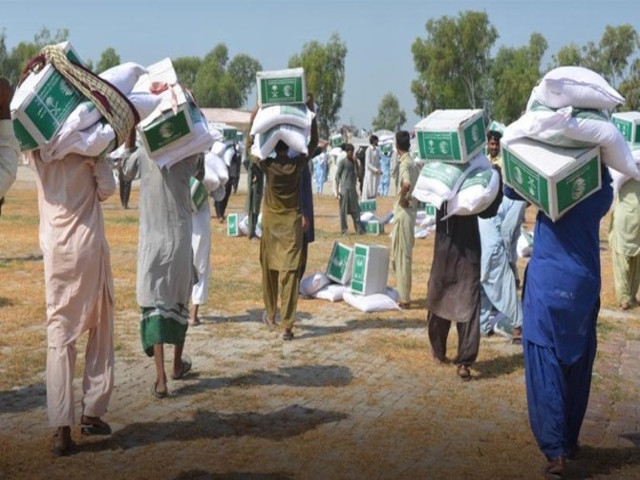 people carrying aid distributed by king salman humanitarian aid and relief center ksrelief in flood affected areas of pakistan photo express