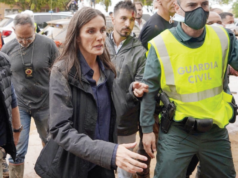 queen letizia of spain with mud stains on her face approaches to speak with a town resident during the spanish royal couple s visit to paiporta in the region of valencia eastern spain photo afp