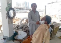 in a dusty roadside corner of rawalpindi a barber shaves a customer seated on a makeshift chair serving low income workers despite rising health concerns photo express