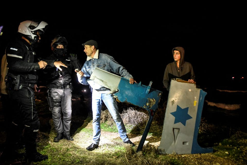 policemen speak with israelis as they hold parts of a military helicopter at the shore after it crashed off the coast of the mediterranean near haifa as local media said israel january 3 2022 reuters