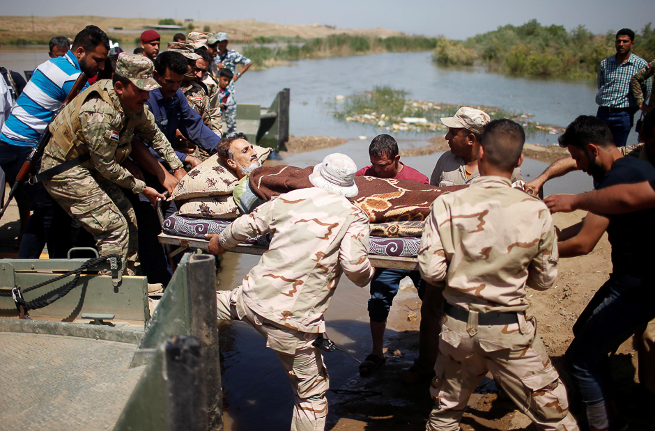 Iraqi forces evacuate a wounded displaced man as he crosses the Tigris by a military boat after the bridge has been temporarily closed, south of Mosul, Iraq. PHOTO: REUTERS