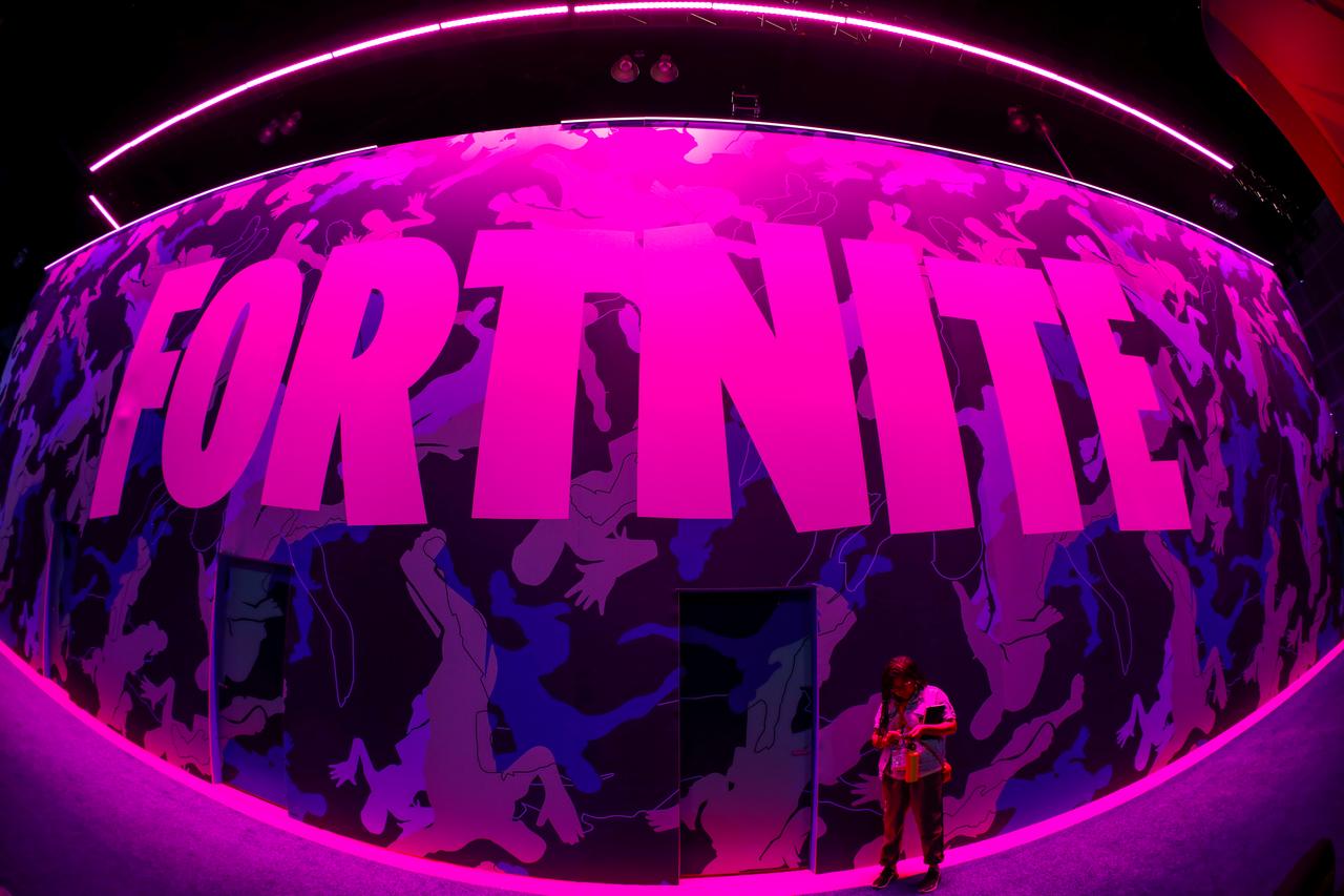 an attendee stops to text next to epic games fortnite sign at e3 the annual video games expo revealing the latest in gaming software and hardware in los angeles california us june 12 2019 photo reuters