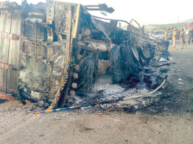 security personnel stand guard near a charred vehicle in musakhail district photo afp security personnel stand guard near a charred vehicle in musakhail district photo afp
