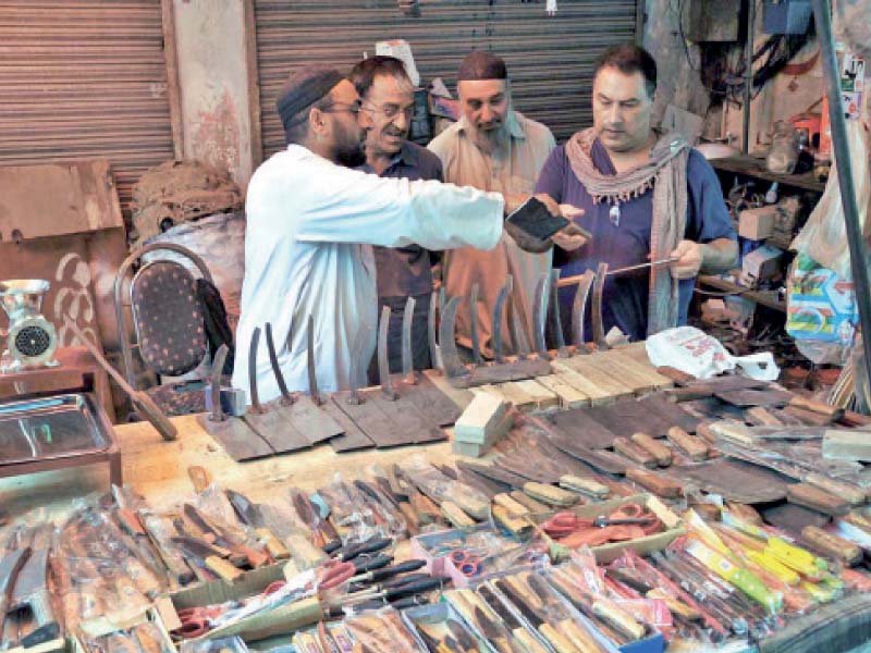 a man checks a meat cleaver at stall selling knives axes and other items for butchers in islamabad before eidul azha pho to app