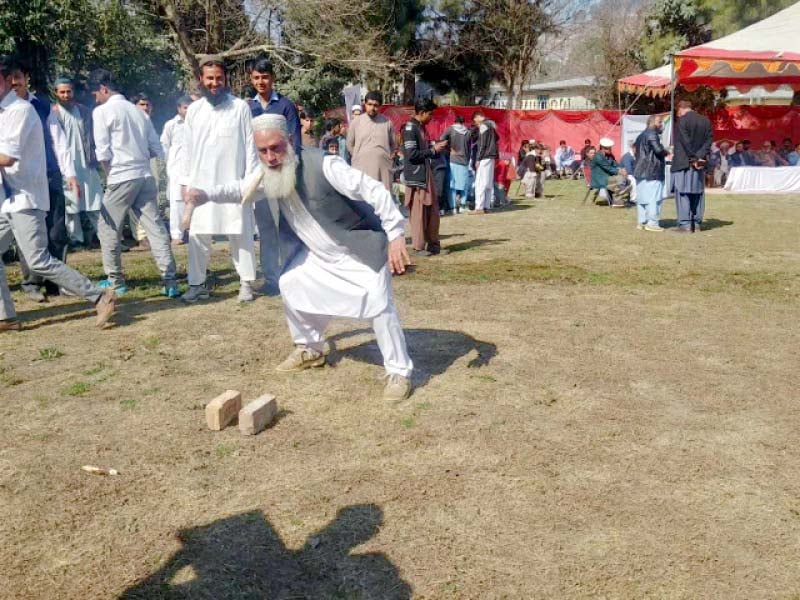 an elderly man swings the stick known as danda in the air to hit one of the tapered ends of another smaller stick called gilli as he participates in a gilli danda competition at the hazara traditional games being held in abbottabad photo express