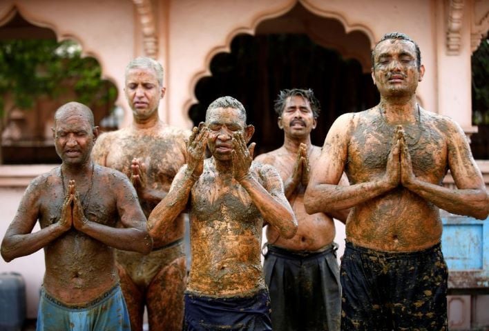 People pray after applying cow dung on their bodies during 