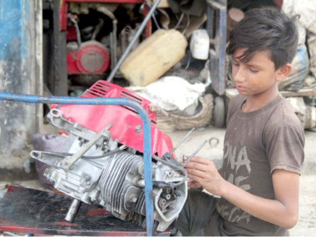 a boy works on a motorcycle engine at a roadside workshop photo online file a boy works on a motorcycle engine at a roadside workshop photo online file