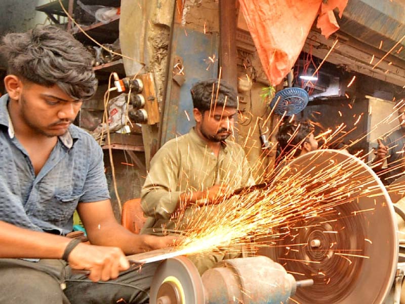 a youth sharpens a cleaver at a roadside stall in karachi ahead of eidul azha many small businesses like sale and sharpening of knives and barbeque equipment sprout up around the festive occasion photo jalal qureshi express