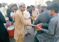 people serve iftar packs and sherbet to commuters on a roadside photo express