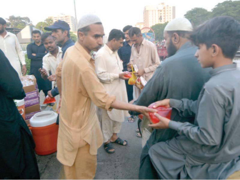people serve iftar packs and sherbet to commuters on a roadside in karachi photo express