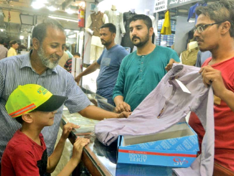 a man selects a dress for his child at a shop in the saddar area of karachi tailors claim they are losing business to readymade garments manufacturers photo jalal qureshi express