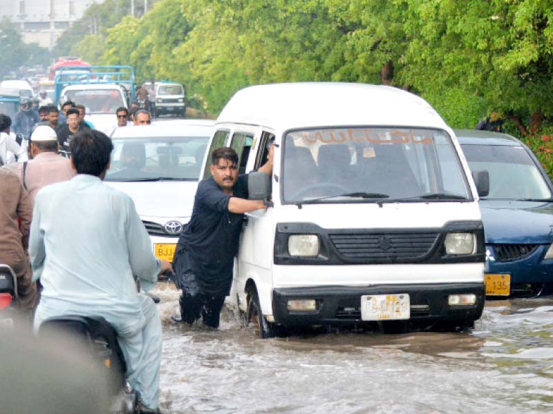 a man pushes his stalled van through rainwater on a road in karachi on tuesday photo jalal qureshi express