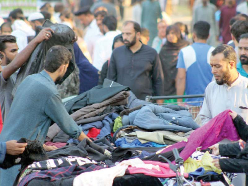 people buy warm clothes from a street stall before the arrival of the winter season in the federal capital photo raja zafar express