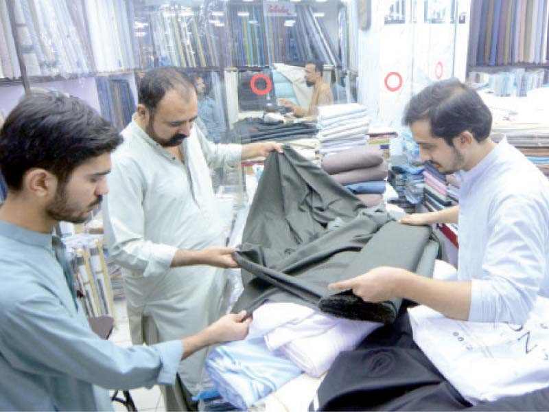 people buy ready made garments at a market instead of going for unstitched fabric as tailoring cost has gone up because of inflation photo express