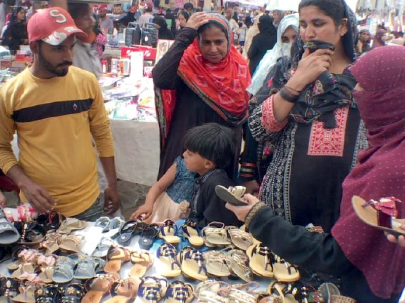 women haggle over price of slippers for a girl at a stall in the saddar area of karachi on monday photo express