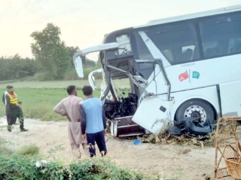 bystanders look at the wreck of a coach that rammed into a tractor trolley near dijkot photo express