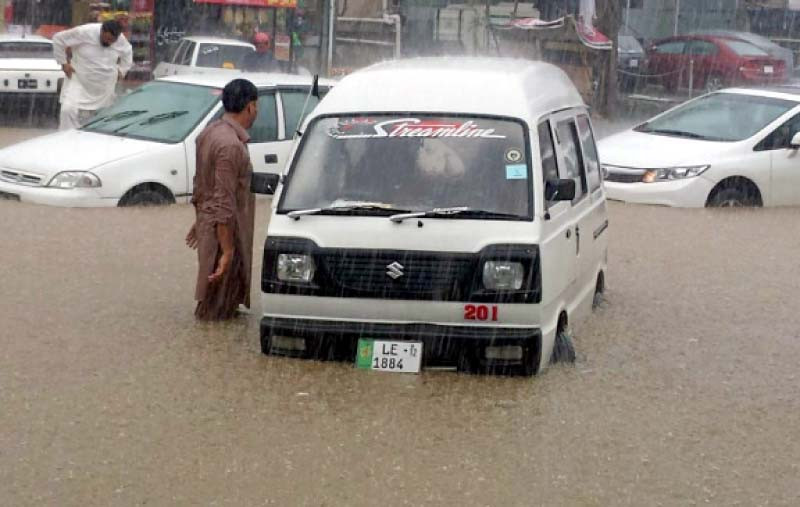 a man stands near a vehicle stuck in water waiting to be rescued during heavy monsoon rain in the city photo online file