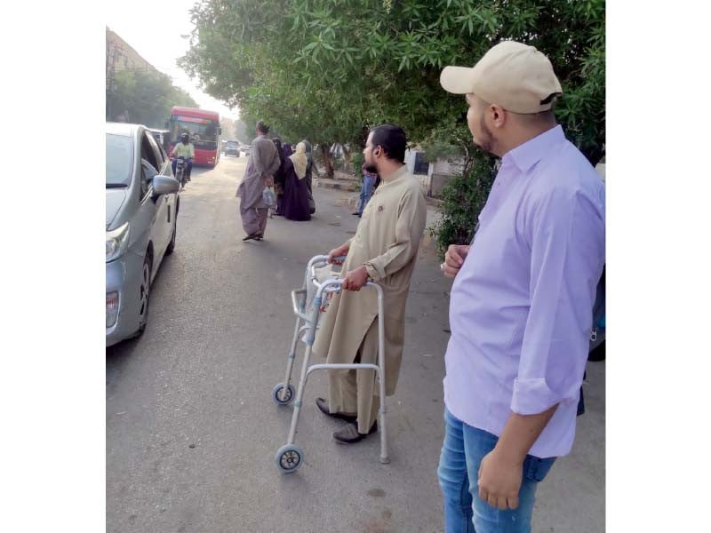 a disabled person waits at a bus stop to embark on an approaching red bus people rarely vacate seats reserved in red busses for persons with disabilities photo express