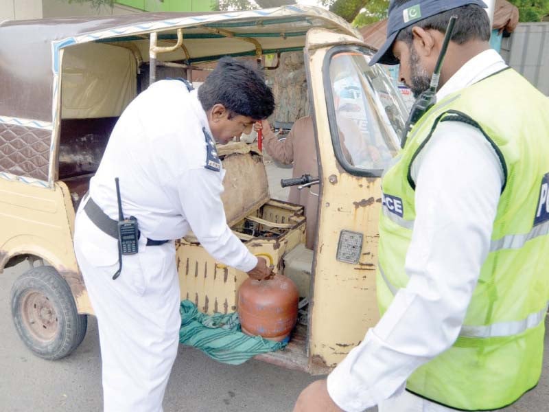 traffic police officers remove a liquefied petroleum gas lpg cylinder from a rickshaw lpg cylinders can explode endangering the lives of passengers photo jalal qureshi express file