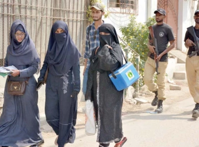 policemen accompany polio workers at a neighbourhood in karachi during the special vaccination drive launched on monday photo jalal qureshi express
