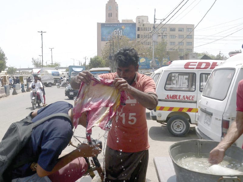 an edhi volunteer pours water on a biker to provide him relief from heat on friday afternoon the weather turned pleasant in the evening after scattered showers photo ppi