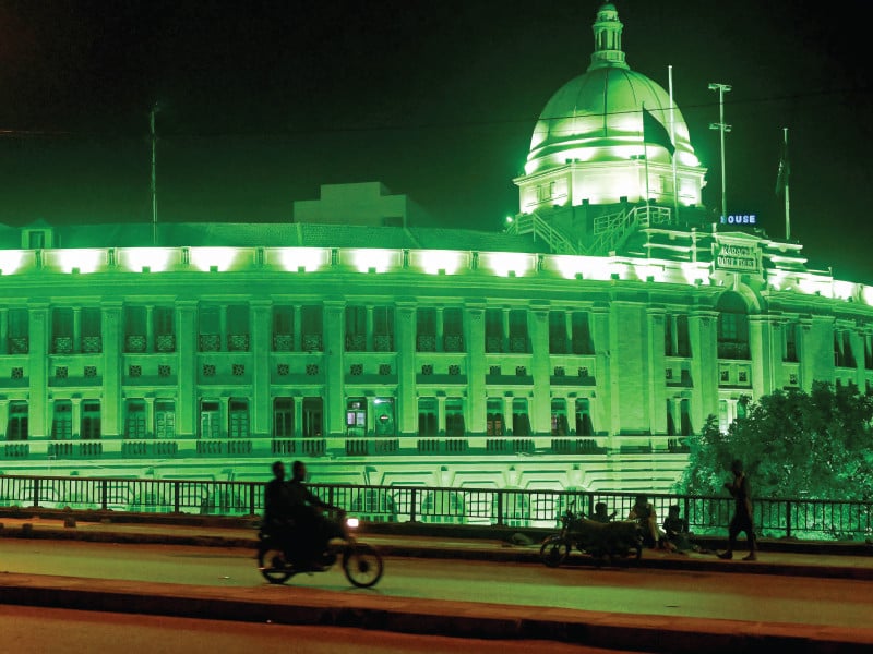 commuters ride past karachi port trust building illuminated in the colour of the national flag in karachi photo afp